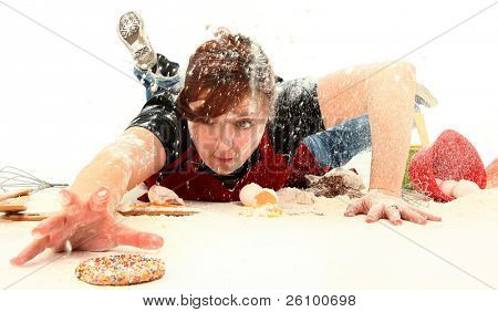 Hungry teen girl diving through baking mess to get the last sugar cookie.