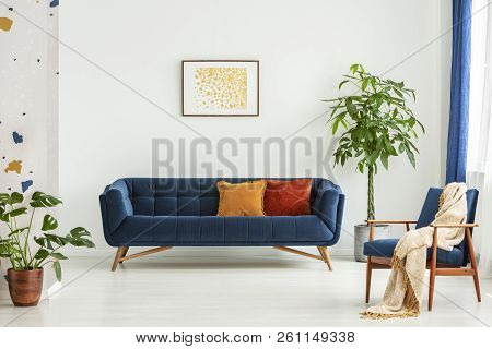 Mid-century Modern Chair With A Blanket And A Large Sofa With Colorful Cushions In A Spacious Living