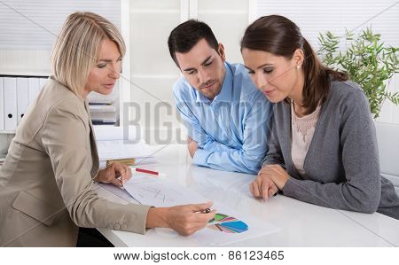 Professional business meeting: young couple as customers and an adviser for finance, investment or insurance.