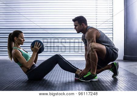 Side view of a muscular couple doing abdominal ball exercise