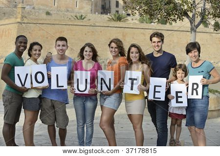 happy and diverse volunteer group holding sign