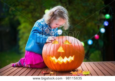 Little Girl Carving Pumpkin At Halloween