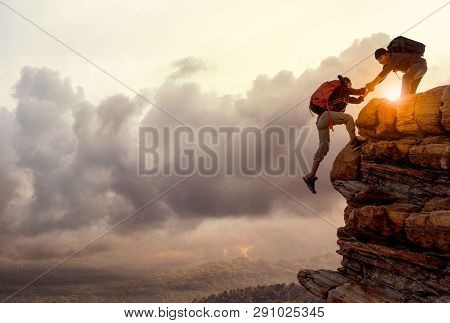 People Helping Each Other Hike Up A Mountain At Sunrise. Giving A Helping Hand, And Active Fit Lifes