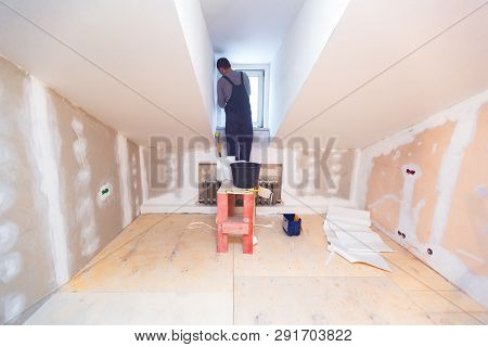 Worker Is Installing Pvc Window From Wooden Platform In Small Room Of  Apartment That Is Under Const