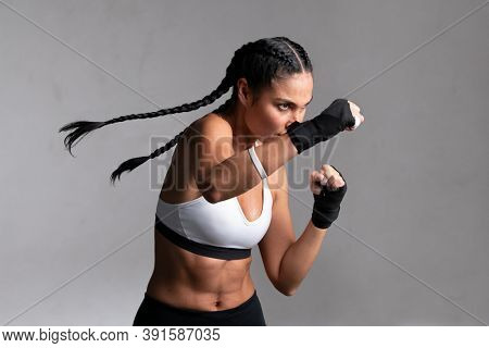 Determined middle aged woman boxer preparing for boxing fight. Fitness mid adult woman preparing for boxing training at gym. Beautiful strong sportswoman in boxing gloves prepared right hand punch.