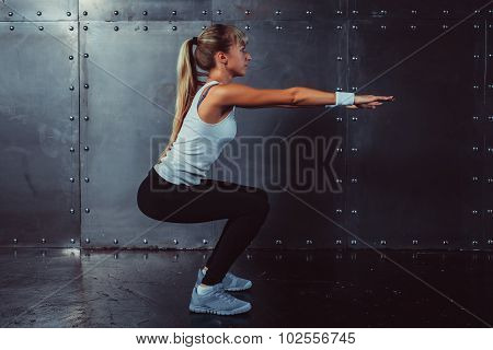 Athletic young woman fitness model warming up doing squats exercise for the buttocks concept sport s