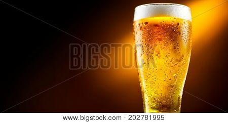 Beer. Cold Craft light Beer in a glass with water drops. Pint of Beer close up isolated on black color background. Border design