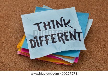 think different concept - motivational phrase on a stack of sticky notes against cork bulletin board