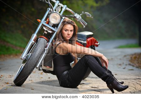 Biker Girl Sitting Next To A Bike