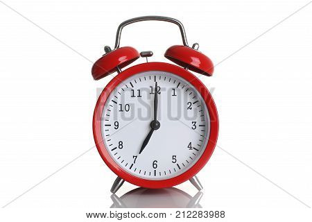 Red alarm clock isolated on white background shows seven o clock in the morning time to get up to wake up and have breakfast morning or evening run to go to work 7 am pm.