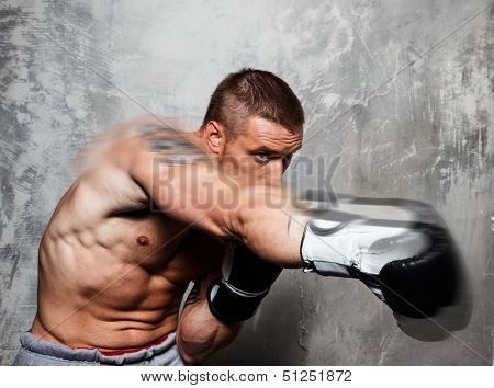 Young man in boxing gloves making punch 