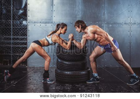 Athlete muscular sportsmen man and woman with hands clasped arm wrestling challenge between a young