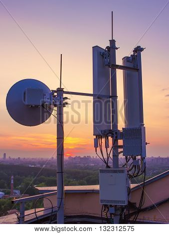 base station with a radio relay antenna on the background of a sunset over the city