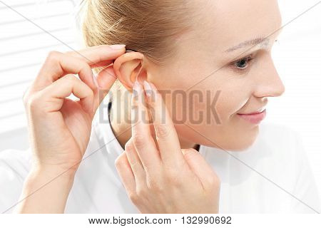 Young woman assumes a hearing aid .