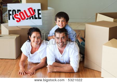 Family In Their New House Lying On Floor With Boxes