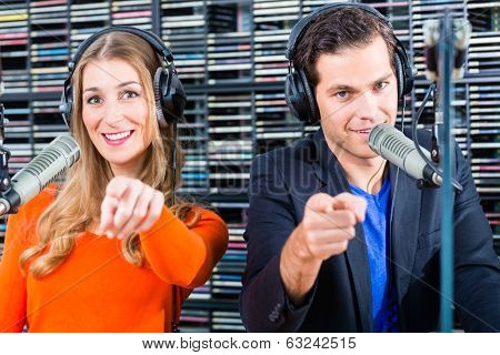 Presenters or moderators - man and woman - in radio station hosting show for radio live in Studio