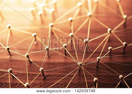 Linking entities. Network, networking, social media, internet communication abstract. Web of gold wires on rustic wood. Shallow depth of field. Intentionally shot in surreal tone.