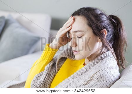 Young Woman With Headache Sitting On Sofa. General Health Problems Concept - Migraine.