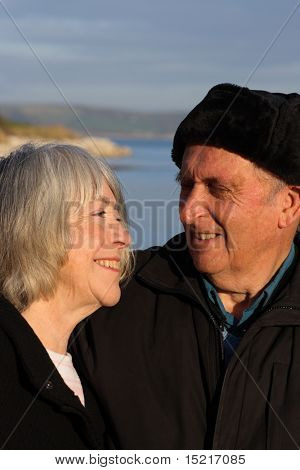 A mature couple enjoy a walk by the seaside in the winter.