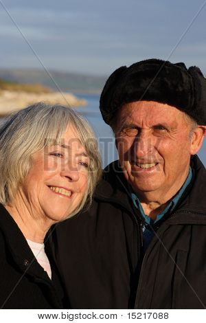 A mature couple enjoy a walk by the seaside in the winter.