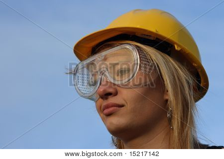 Young female architect apprentice with yellow hard hat and goggles.