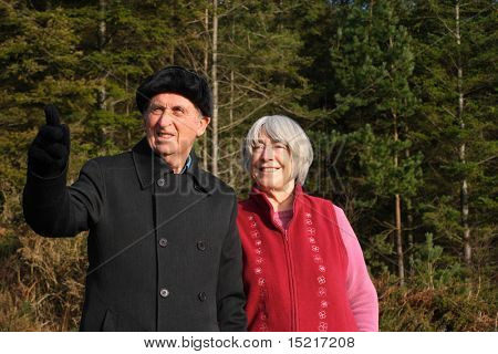 Senior couple enjoy a winter walk through a pine forest.