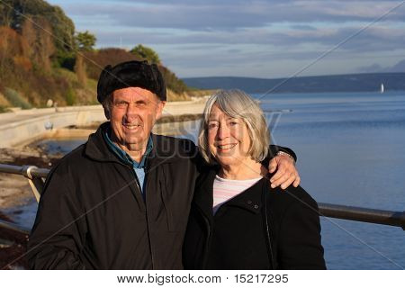 A mature couple enjoy a walk by the seaside in the winter.