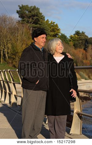 A mature couple enjoy a walk by the seaside in the winter.