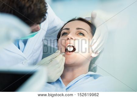 Dentist Examining Patient Teeth With A Mouth Mirror. Dentist Is A Man, Patient Is A Woman. Patient I