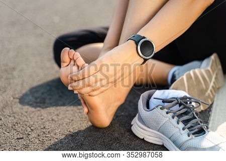 Running Injury Leg Accident- Sport Woman Runner Hurting Holding Painful Sprained Ankle In Pain. Fema