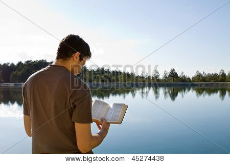 Man Reading Bible By Lake