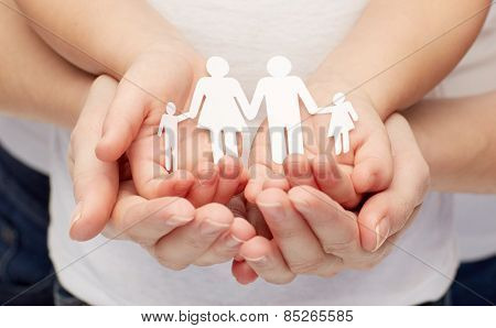 people, charity, family and care concept - close up of woman and girl hands holding paper family cutout