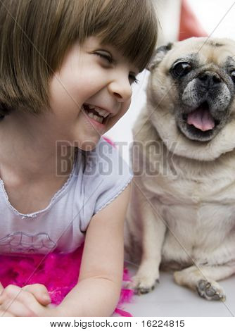 Un bel jeune enfant adorable avec doux sourire en regardant son chien Carlin pour animaux de compagnie