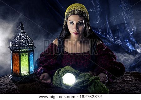 Female fortune teller doing a psychic reading with a cystal ball predicting fate or destiny and the future. The image depicts religion or the paranormal.