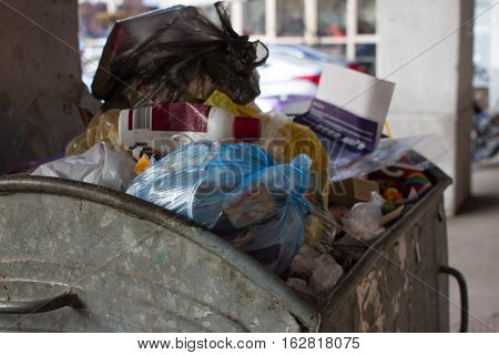 Outdoor trash bin with food waste. Not sorted garbage, yard, stench, filth, carelessness. Steel container