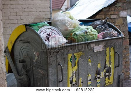 Outdoor trash bin with food waste. Not sorted garbage, yard, stench, filth, carelessness. Steel container