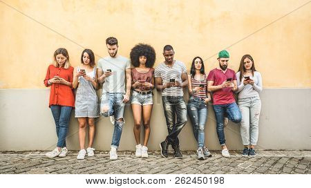 Multiracial Friends Using Smartphone Against Wall At University College Backyard - Young People Addi