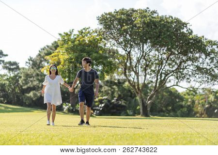 Couple hold ahnd and walk in the park