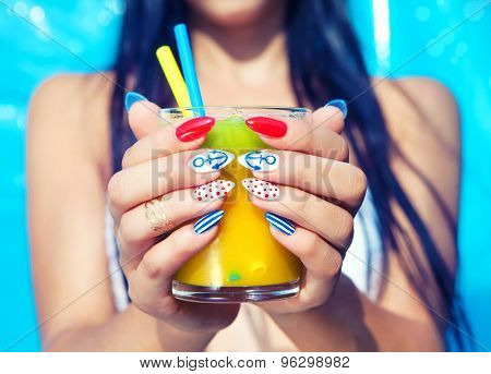 Young woman with marine sailor manicure holding glass of orange juice, summer nail art beauty and drink concept