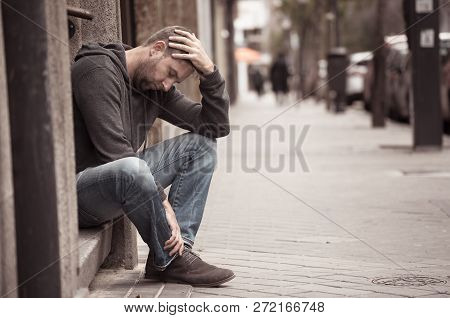 Unhappy Depressed Caucasian Male Sitting On Urban Street Feeling