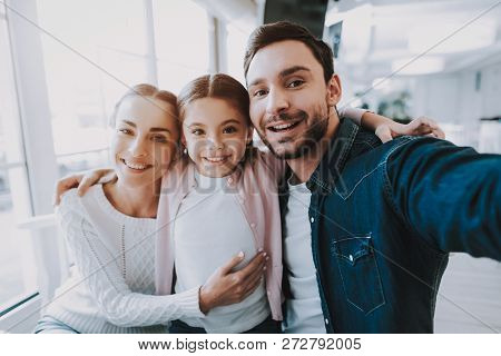 Family Resting In Cafe. Family Is A Mother, Father And Daughter. People Is Doing Selfie On Mobile Ph