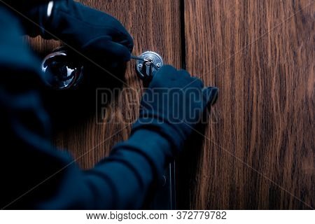 Closeup Of Unrecognizable Robber Cracking Door Lock With Metal Picklock Tool During House Breaking