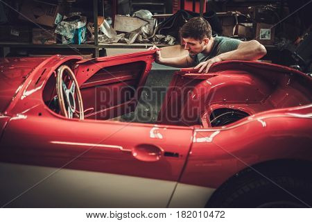 Mechanic working on car body details in restoration workshop