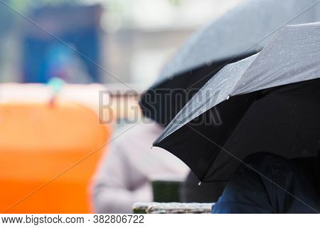 Black Umbrellas, People Sit Outside In The Rain