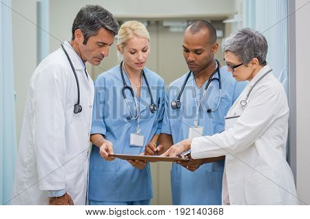 Group of senior doctors and young nurses examining medical report of patient. Team of doctors working together on patients file at hospital. Medical staff analyzing and working at clinic.