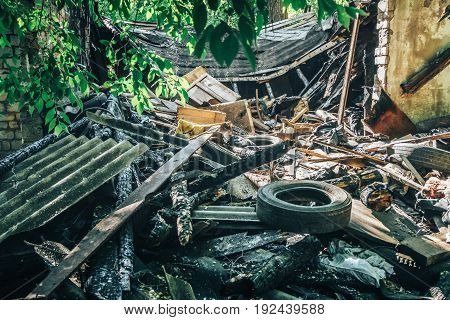 Large pile of rubbish, old tires, debris of a building against the ruined house, can be used as consequences of war, earthquake, hurricane or other natural disaster