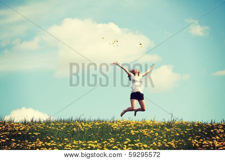 Happy woman jumping on blossom meadow. Beautiful day on field.