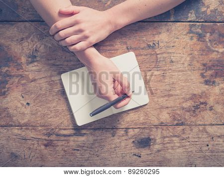 Woman Writing In Notepad At Wooden Table