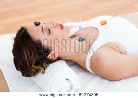 Woman being hypnotized with stones on her body on wooden floor