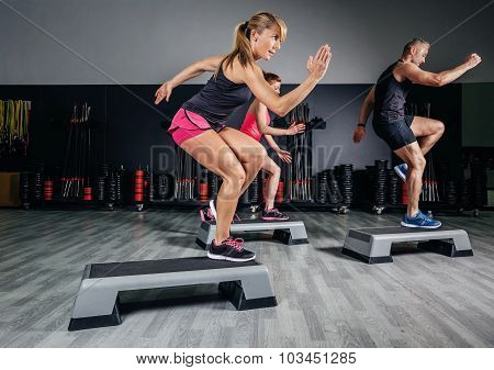 Woman trainer doing aerobic class with steppers in gym